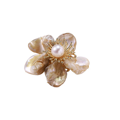 Flower-shaped brooch with iridescent shell petals, freshwater pearl center, and gold-plated radiating details.
