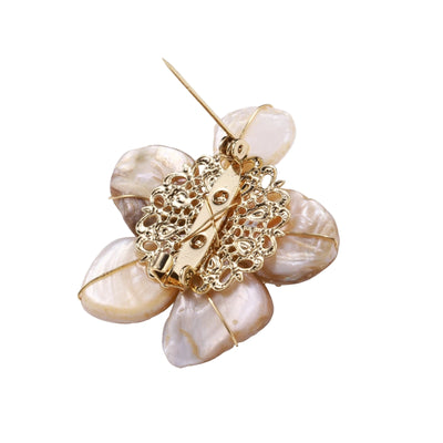 Flower-shaped brooch with iridescent shell petals, freshwater pearl center, and gold-plated radiating details.