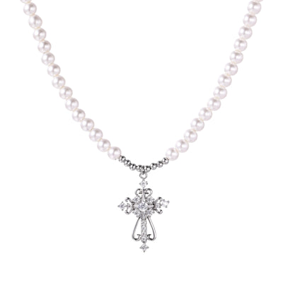 White pearl necklace with ornate silver cross pendant featuring zirconia crystals on cream background.