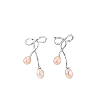 Rhodium-plated silver earrings with organic vine curves and two peachy freshwater pearls on cream background